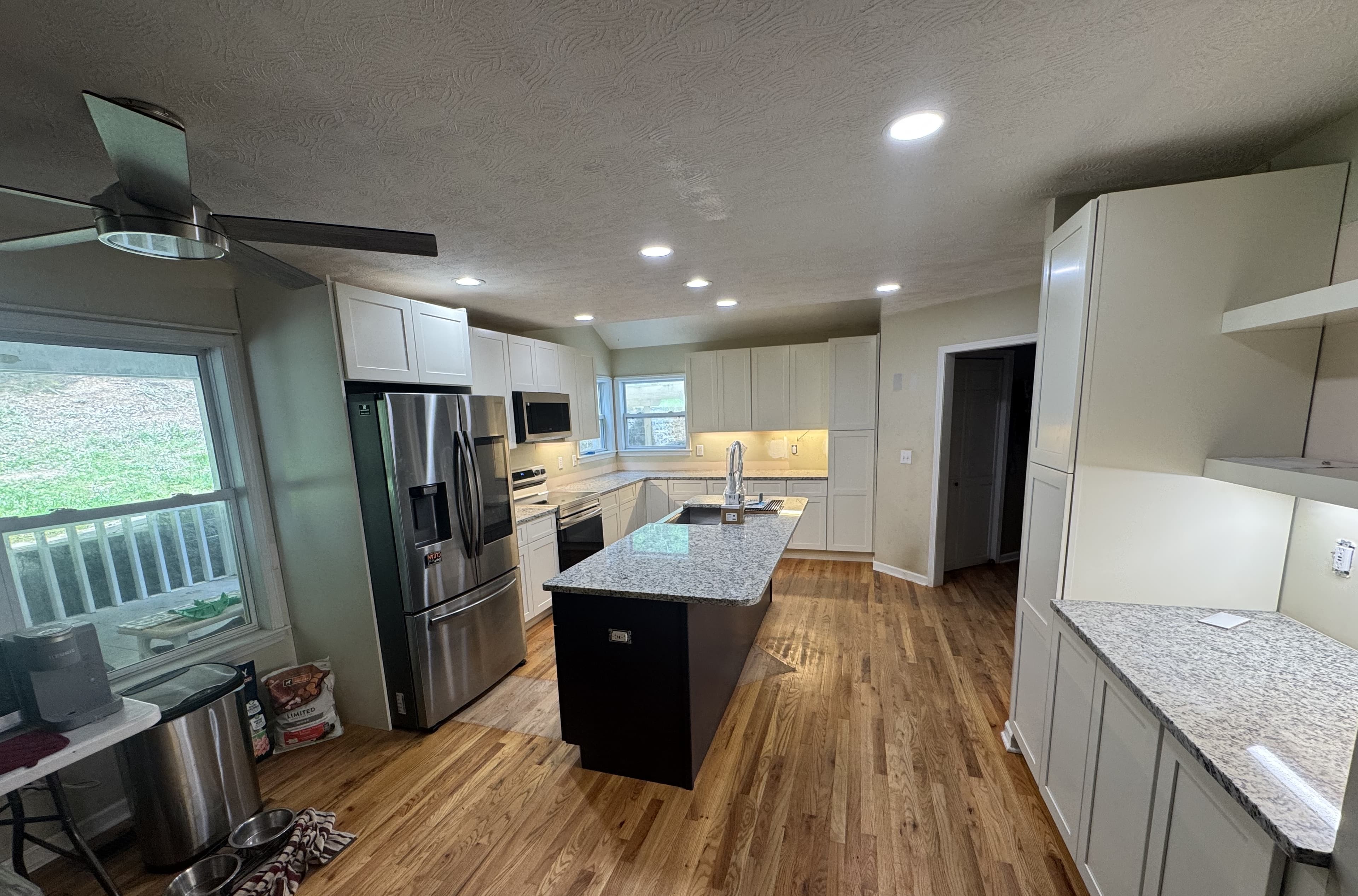 Completed kitchen remodel with white shaker cabinets and granite island by S&T Construction